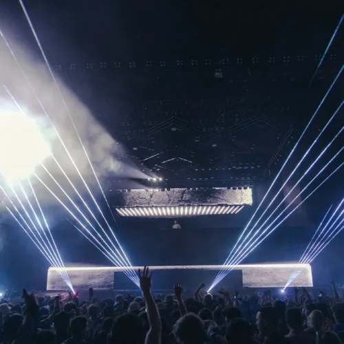Calvin Harris on a laser lit stage in front of a crowd at a concert produced by 1314