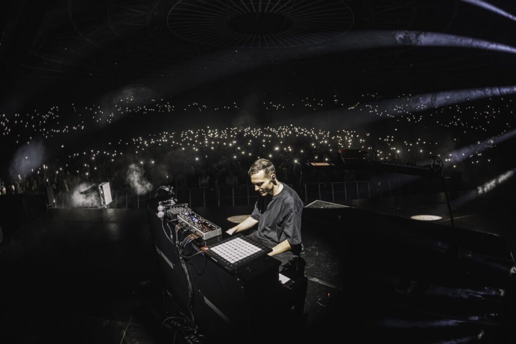 Ben Böhmer on the stage at one of his concerts produced by 1314 with a huge audience holding up flashlights