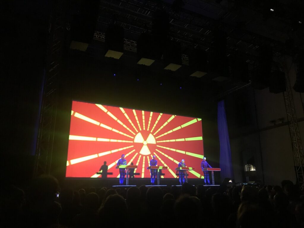 Stage with a red Backdrop with four people on it of a Kraftwerk concert produced by 1314